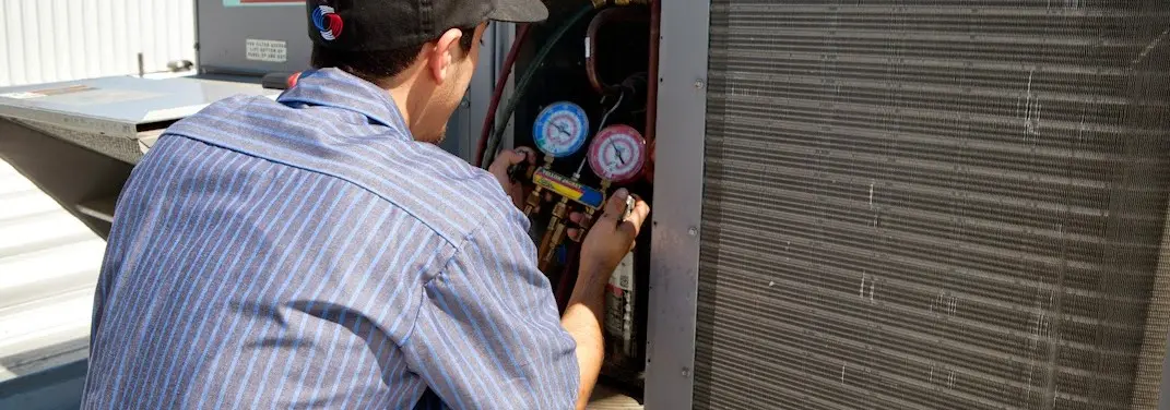 HVAC technician servicing a condenser unit in Champaign