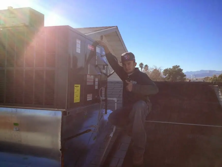HVAC technician performing Air Duct Repair on a rooftop unit in Champaign